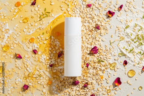 White bottle surrounded by oats and rose petals natural skincare product flat lay