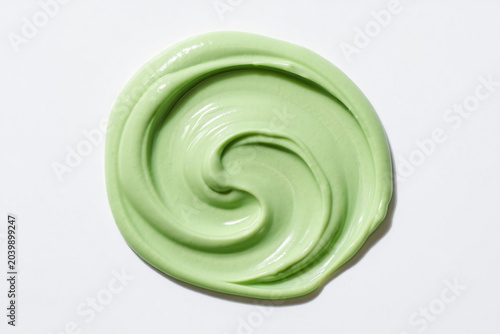 Green swirl cream texture on white background beauty product sample