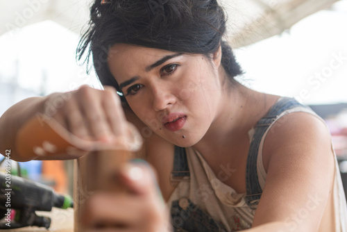 Tableau sur toile Young Asian woman concentrating while working with tools at a workshop