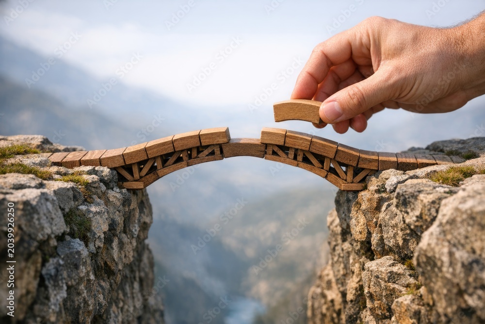 Obraz premium A person standing on a wooden bridge spanning a deep cliff, with a scenic view in the background