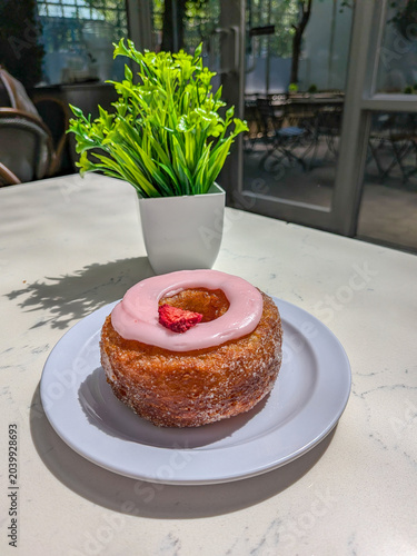 Croissant style donut with pink frosting