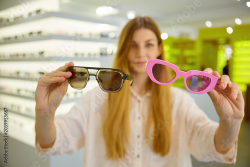 Obraz na płótnie Woman examining different glasses, holding them in front of her