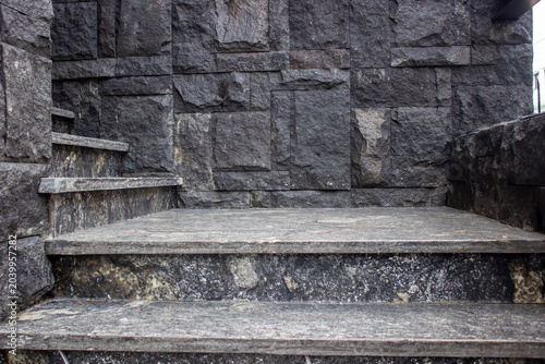 Building entrance staircase with dark grey granite marble steps perfectly matching the textured black andesite natural stone cladding wall.