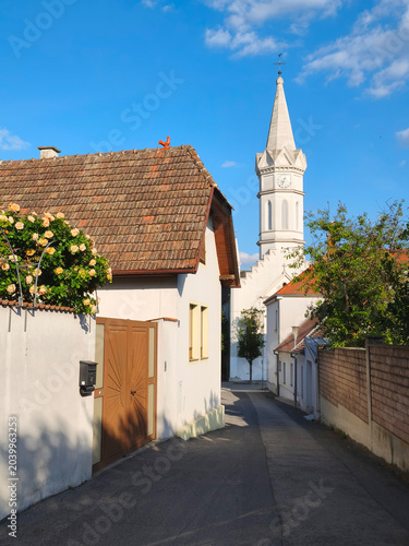 Mörbisch am See, Austria - 24 May 2026: Charming alley with church tower in Mörbisch am See