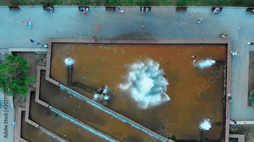 Aerial drone view of the famous Sadko Fountain in the center of Sumy, Ukraine during a hot summer day. People relax around the fountain, children play near the water