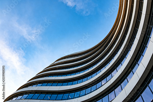 Modern Curved Office Building with Glass Windows Against Clear Blue Sky