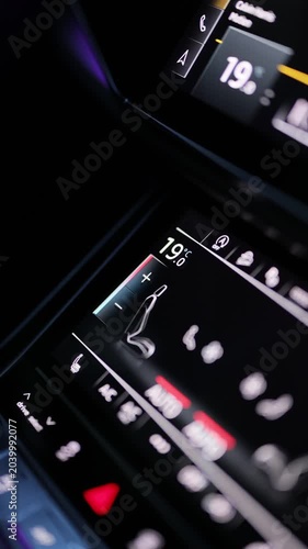 Vertical video of a hand adjusts the climate control system in a car. Male hand regulating the air conditioning control in a car. The warm glow of the controls shows the set temperature