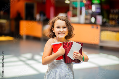 Little girl kid with popcorn and drink in movie theatre cinema