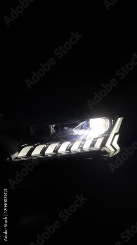 Vertical format video of Car Front Led Light with black Background. Adaptive Laser Headlight turning on switching of car LED headlights in night. New modern electric hybrid car bi-led matrix headlamp
