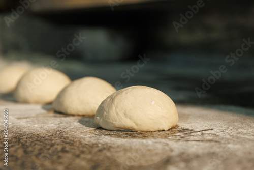 Fotografie Fresh pizza dough balls resting on wooden kitchen table, authentic Italian artis