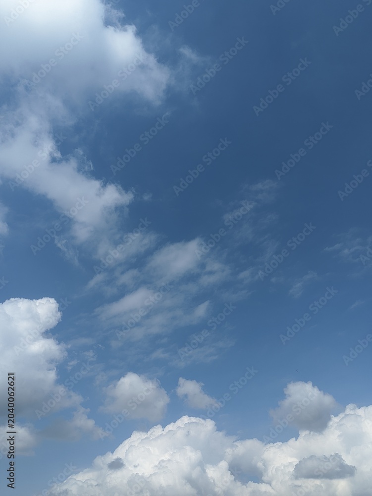 Obraz premium Blue sky background with fluffy white cumulus clouds. Natural background with copy space for background, template, summer concepts, and graphic design elements.