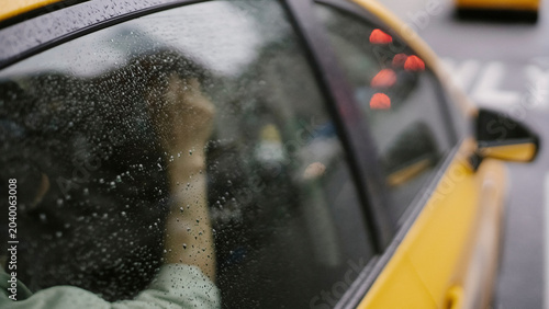 Foto Rain streaked taxi window shows passenger silhouette during wet city commute