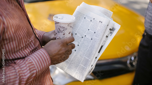 Cuadro en lienzo Passenger holds folded city map or newspaper beside yellow taxi hood