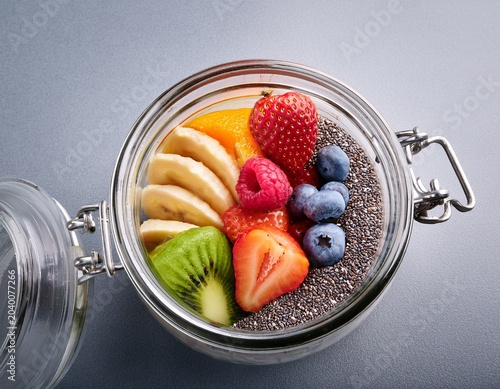 fresh fruits and nuts in jar with chia seeds on grey surface for healthy lifestyle and nutrition concepts