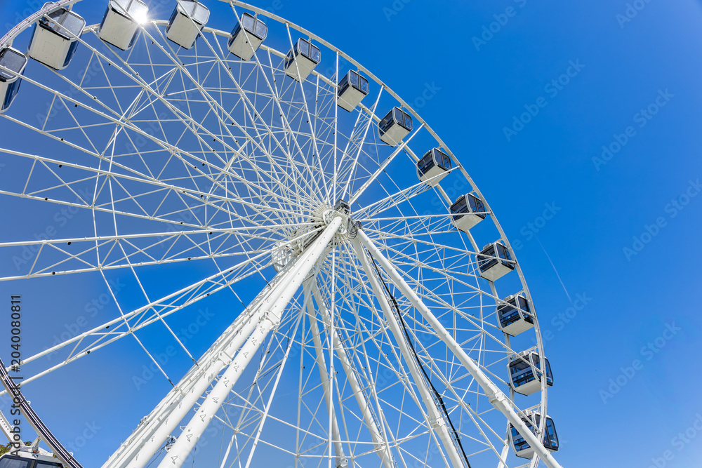 Obraz premium Ferris wheel viewed from below against clear blue sky with geometric structure and copy space