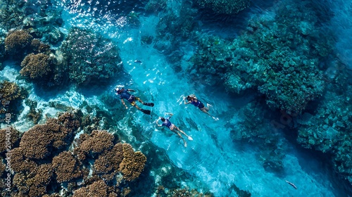 Aerial view of snorkelers swimming over a vibrant coral reef in crystal clear turquoise ocean water for summer vacation concepts