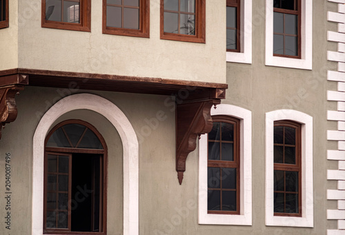 Traditional ottoman style house facade with wooden windows. Ottoman architecture facade featuring rustic wooden window frames, an elegant archway and decorative corbels on plaster walls.