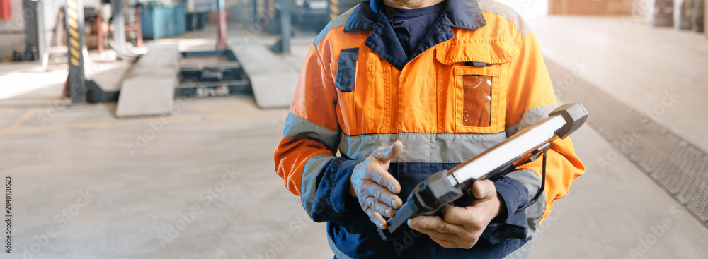 Fototapeta premium Mechanic using tablet for vehicle diagnostics in service bay for truck mining