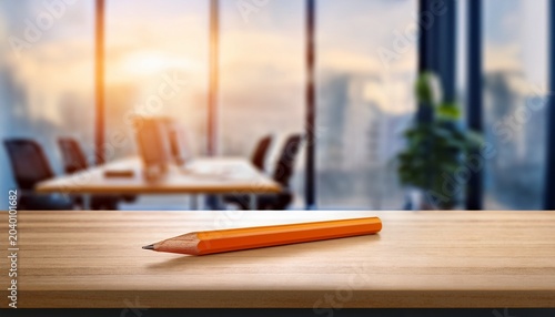 orange wooden pencil on wooden desk in modern office with blurred windows