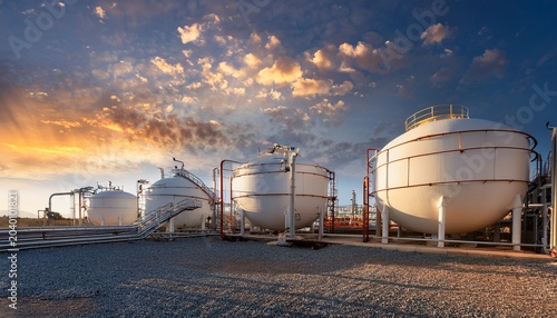 tank compressor station at oil and gas facility under a dramatic sky