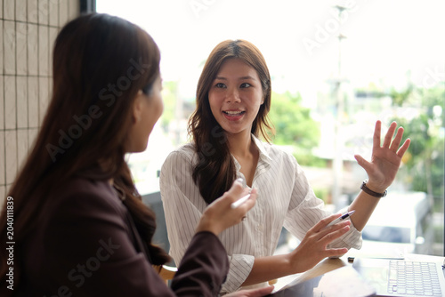 Two women work together inside a conference room.