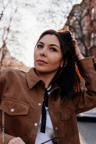 Beautiful young woman enjoying a sunset in Prague city. Stylish girl in a fashionable outfit posing outdoors near historic architecture in warm golden light. Urban fashion and lifestyle concept.