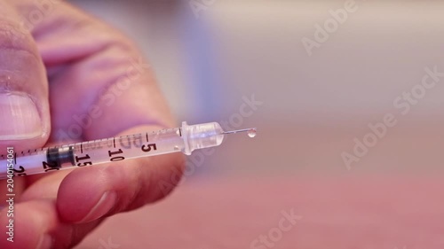 Person holding a syringe with insulin drops falling from the needle