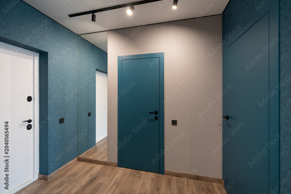 Fototapeta premium Modern hallway interior with blue accent walls and floor-to-ceiling mirror