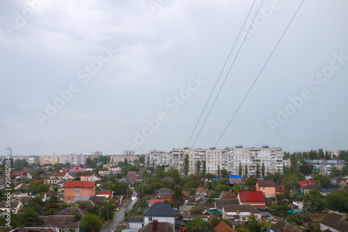 Bild auf Leinwand Raindrops scatter across a window revealing a blurred view of the urban district of Mykolaiv, Ukraine, where grey skies and distant buildings create a calm, reflective rainy atmosphere scene today