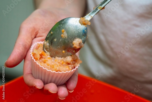 Placing minced meat with carrots into a silicone mold using a metal spoon for meal preparation