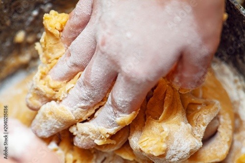 Kneading a stiff honey-yellow dough by hand, preparing for homemade baking