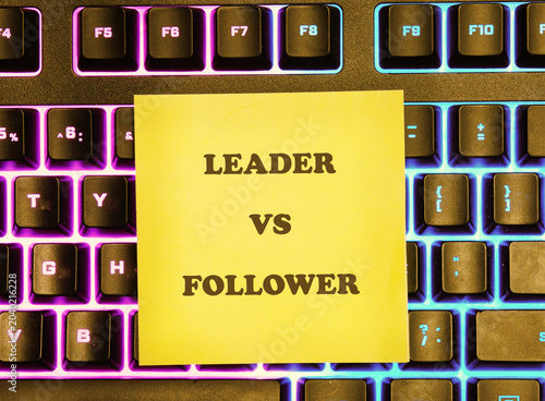 A yellow sticky note displays Leader VS Follower in bold text on a modern computer keyboard with colorful backlighting