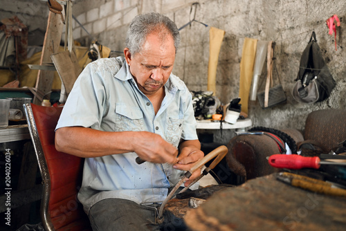 Bild auf Leinwand Artisan male cobbler repairing leather shoes in workshop