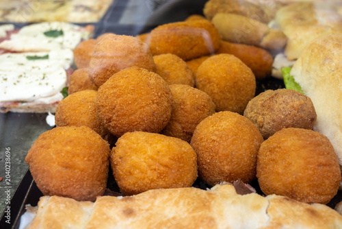 Street food in Italy, Sicilian arancini Arancini di Sicilia traditional Italian fried rice balls with golden crispy coating and different filling