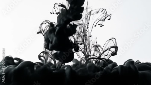 Black ink dispersing in water creating abstract shapes against a white backdrop