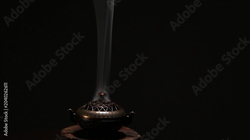 Blue texture smoke from incense aroma stick in vintage old design metal box motion rising above on copy space dark background. Meditation, yoga, wellness, aroma calm relaxation concept