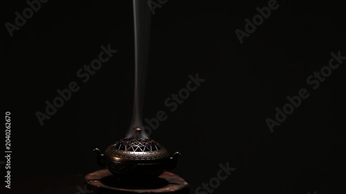 Blue texture smoke from incense aroma stick in vintage old design metal box motion rising above on copy space dark background. Meditation, yoga, wellness, aroma calm relaxation concept