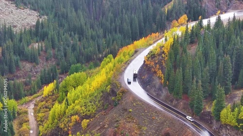 Aerial view of traveling cars in Colorado fall landscapes along Million Dollar Highway with views of fall foliage trees in San Juan Mountains during autumn season - 4K Drone
