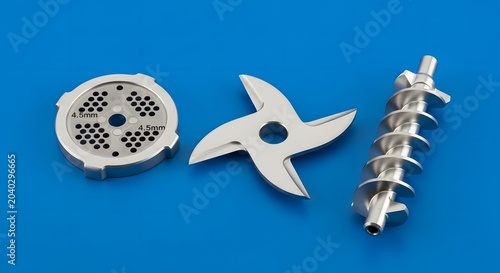 Shiny metal components of a food grinder, including a sharp four-bladed cutter, a perforated disk, and a sturdy spiral auger, essential for culinary preparation