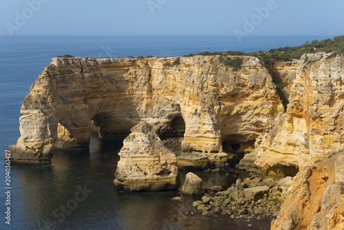 Steep cliffs and craggy rocks jut out of the calm sea on a clear day, Praia da Marinha, Lagoa, Rocky Algarve, Algarve, Portugal