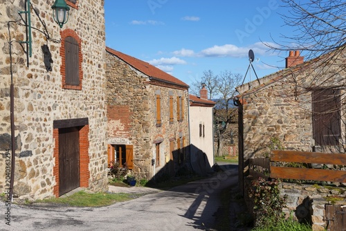 Eine ruhige Dorfstraße mit steinernen Häusern und Fensterläden unter einem sonnigen, blauen Himmel, Léotoing, Leotoing, Haute-Loire, Auvergne-Rhône-Alpes, Auvergne-Rhone-Alpes, Frankreich