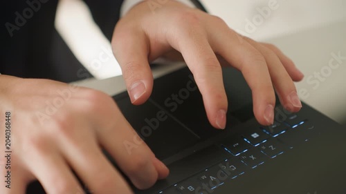 Closeup hands typing laptop keyboard in bright office, calm professional in suit preparing report, measured keystrokes and deliberate pace, natural daylight on desk, focused meeting prep