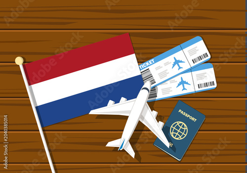 Flag off Netherlands with passport and toy airplane on wooden background. Flight travel concept
