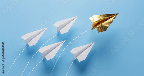 Unique leadership concept with shiny gold paper aircraft paving a new path on blue backdrop. Think differently and business innovation concept with a gold plane leading white airplanes