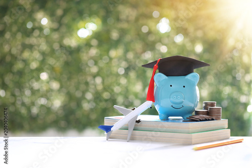 Graduation cap on piggy bank and airplane model on books  representing scholarship savings  international education fund  and study abroad investment on green bokeh background investment and scholarsh