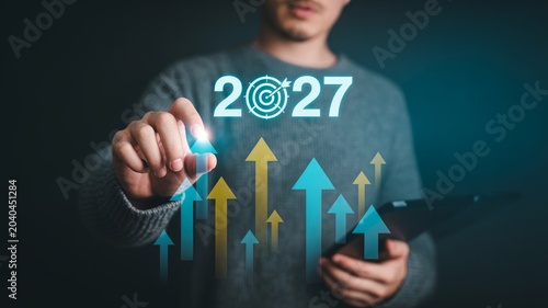 Man points at year 2027 target with upward arrows, symbolizing growth and future business goals achievement.