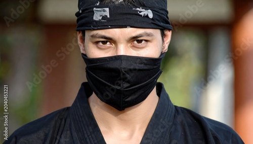 Close-up portrait of a masked man in a black ninja outfit, staring intently at the camera.