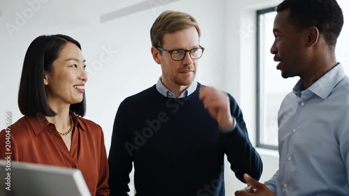 Three colleagues discussing a project on a computer in an office