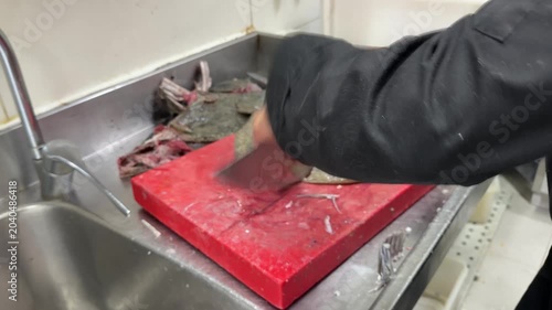 Professional chef cleaning and preparing fresh flatfish in a restaurant kitchen