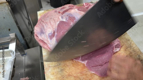Butcher skillfully slicing a large piece of beef with a cleaver
